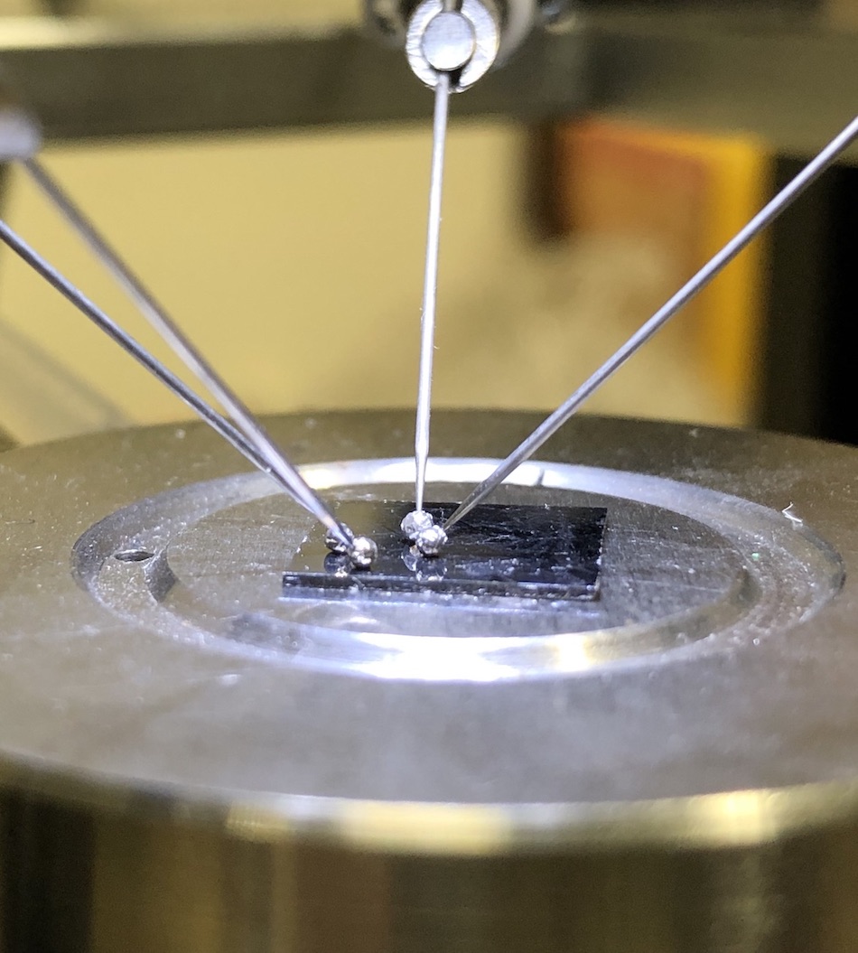 An experiment setup with metallic probes resting on a square photodiode.